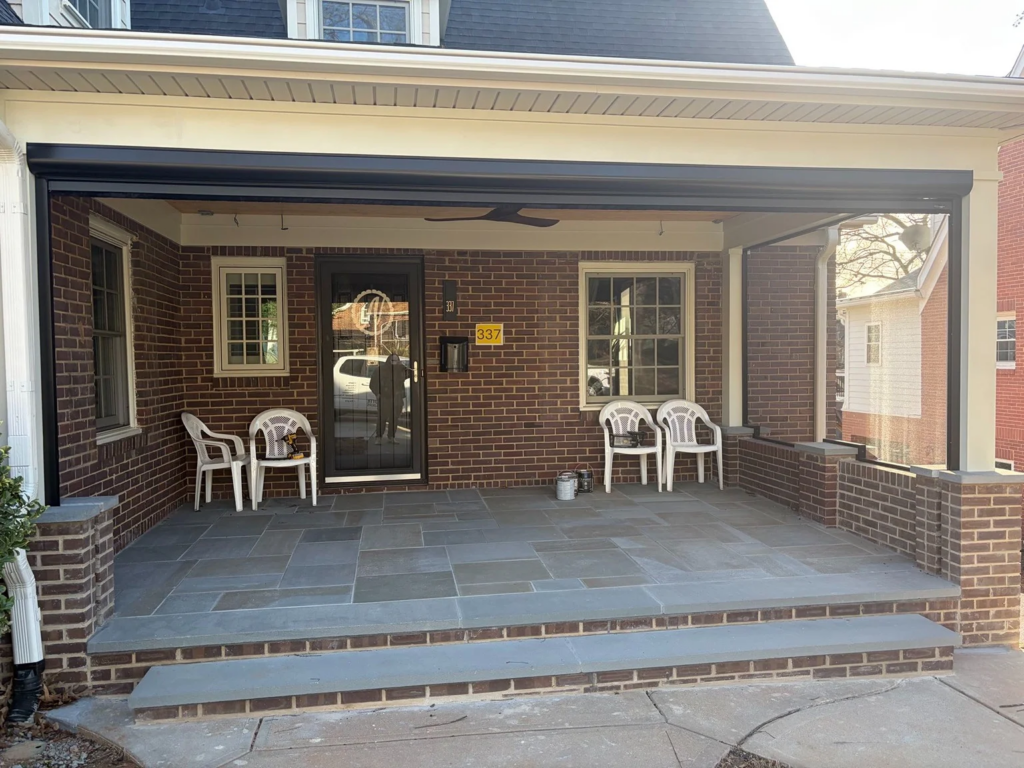 A gray stone patio with white lawn chairs