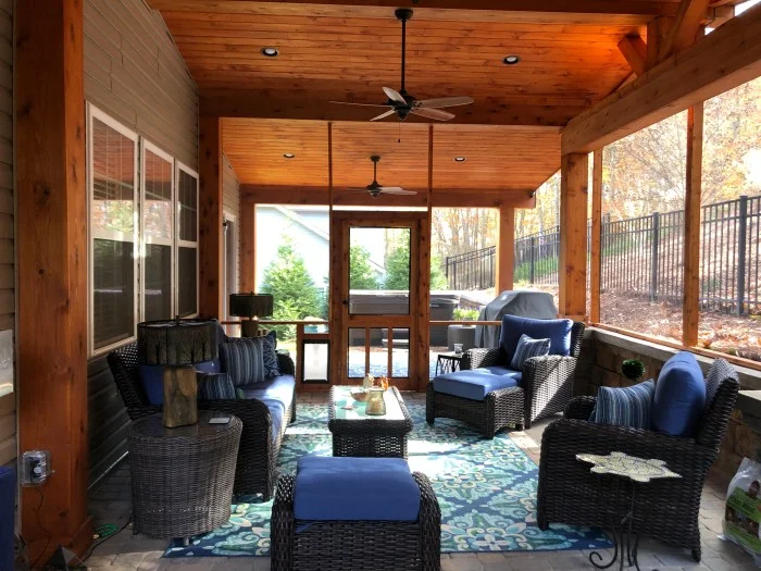 A screened porch with blue wicker furniture
