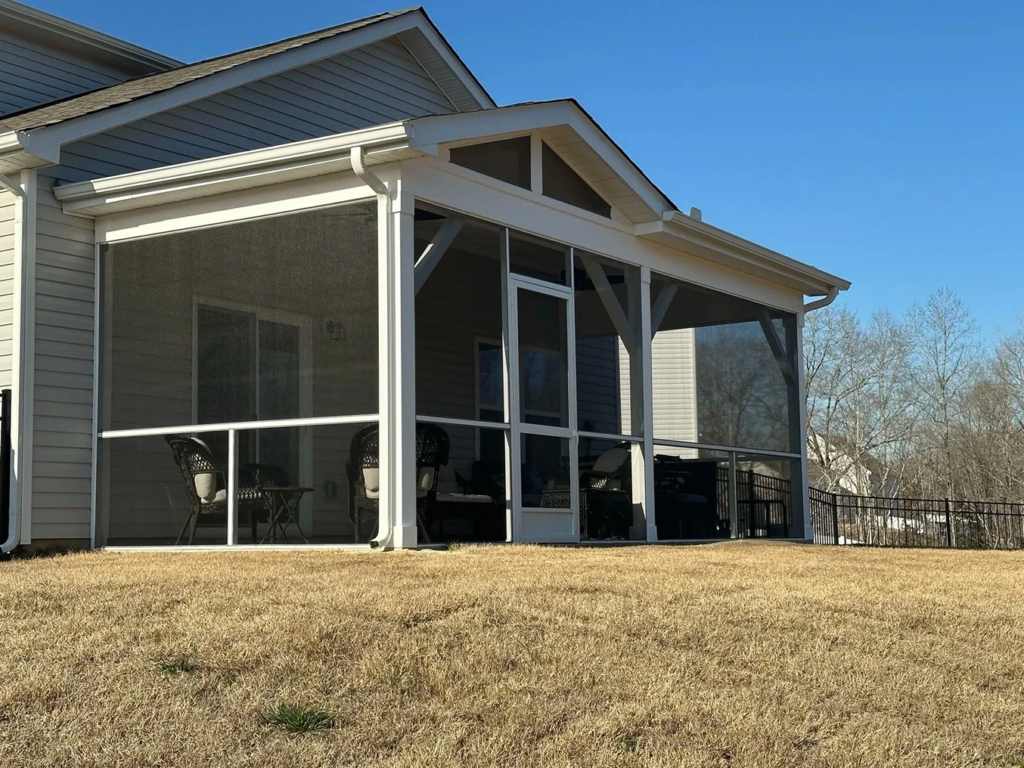 Screened porch floor materials shown in a covered backyard porch with dark screens and white framing