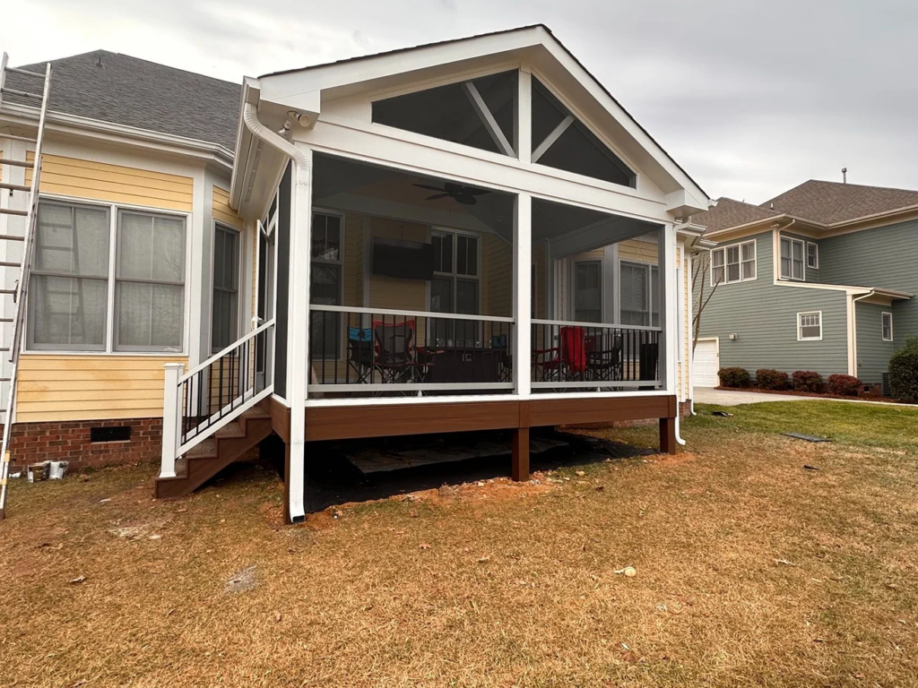 Large screened porch addition with white posts, dark railing, and a raised deck-style floor