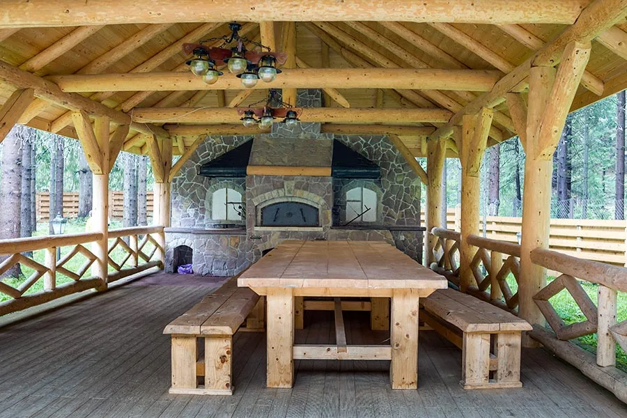Rustic wood pavilion with a stone outdoor kitchen